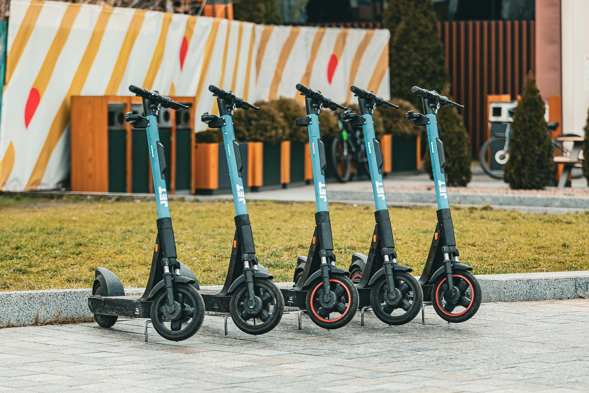 Group of five electric scooters neatly lined up outdoors, ready for rental use.