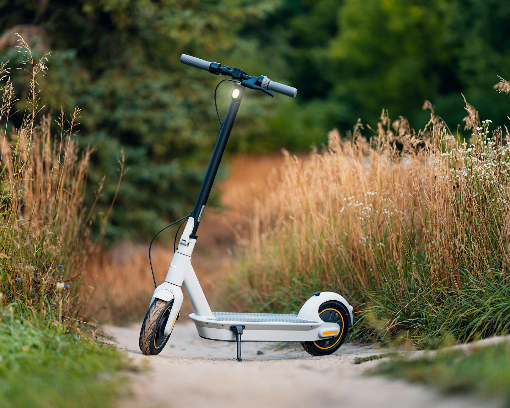 White electric kick scooter standing on a nature path, Segway Ninebot Max style